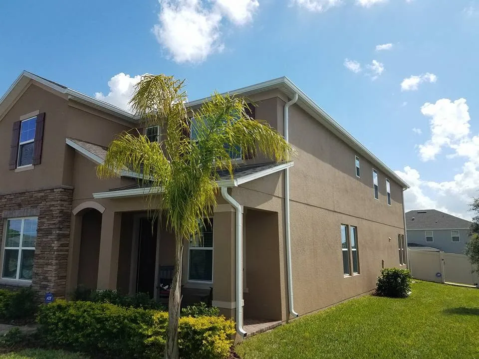 Tan stucco two story home white gutters downspouts queen palm, Sanford